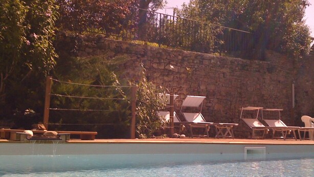 A swimming pool with lounge chairs and a stone wall in the background. - 2* gîte on the ground floor of an old pottery in the center of Dieulefit (Dieulefit)