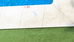 A swimming pool with clear blue water, a tiled edge, and a green area at the bottom. - Cubo’s La Terraza del Mar / free wifi / sea views (Algarrobo)