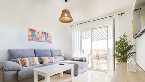 A modern living room with a grey sofa, a white coffee table, and a wicker pendant light. There is a large window with a view of the outside. - Cubo’s La Terraza del Mar / free wifi / sea views (Algarrobo)