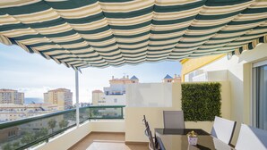 A balcony with a striped awning, a glass table, and a chair. - Cubo’s La Terraza del Mar / free wifi / sea views (Algarrobo)