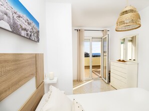 Relax in a spacious room with a large bed, bedside table, and balcony offering a view of the sea and city.