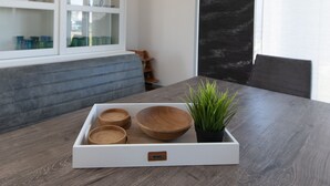 Un vassoio di legno con ciotole e una pianta in vaso su un tavolo.