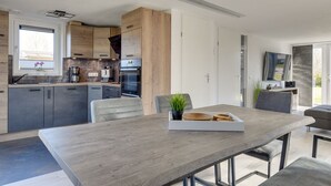 Una cucina moderna con mobili scuri, un piano di lavoro in legno e un'area pranzo con tavolo e sedie.