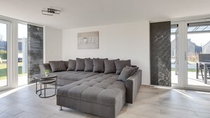 Un soggiorno moderno con un divano componibile, un piccolo tavolino rotondo e un cartello con la scritta 'HOME'.