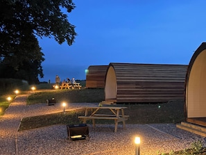 En campingplads med træhytter, picnicborde og grill.