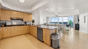 A modern kitchen with wooden cabinets, a dishwasher, and a large island. - Newly Renovated Condo with Bay Views! Complimentary Boat Slip! (Orange Beach)