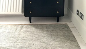 A black dresser with gold knobs, a potted plant on top, and a white radiator in the background. - Stylish Notting Hill flat near Portobello Road (London)