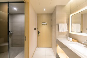 Un baño moderno con cabina de ducha de vidrio, puerta de madera, tocador con espejo y un perchero para toallas.
