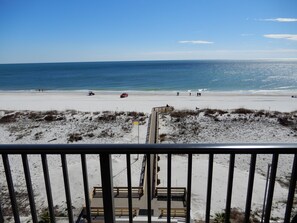 Une vue sur la plage depuis un balcon doté d’une terrasse en bois et d’une rambarde.