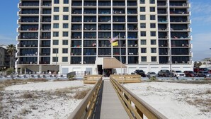 A multi-story hotel with balconies, a covered entrance, and a parking area. - Beachfront condo at Island Winds West in Gulf Shores (Gulf Shores)