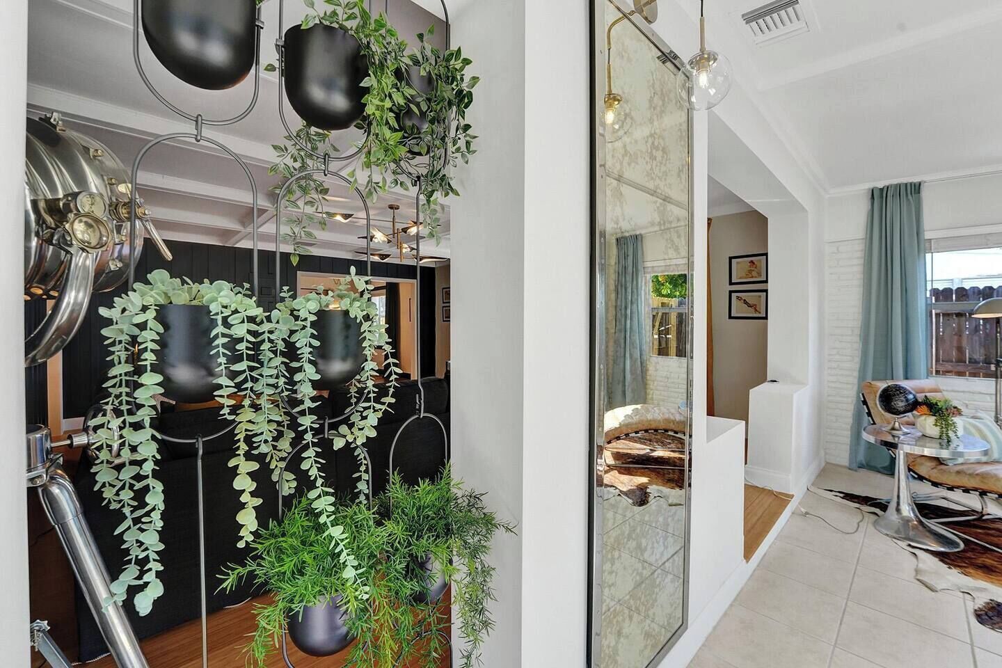 Un interior moderno con un espejo grande que refleja una habitación, un sofá y una zona de comedor con mesa y sillas.