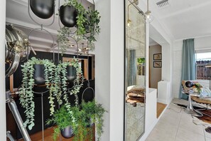 A modern interior with a large mirror reflecting a room, a sofa, and a dining area with a table and chairs. - Stylish Pet Friendly Home with Private Pool Oasis (Fort Lauderdale)