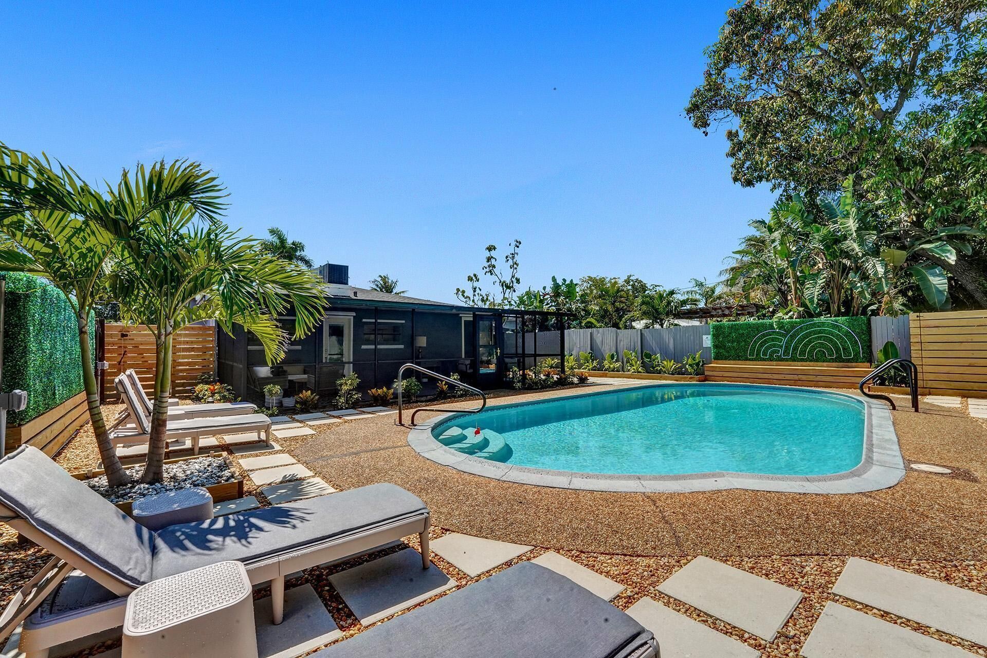 Un patio trasero con piscina, sillas de descanso y una casa moderna.