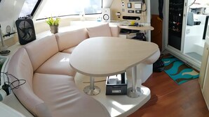 A modern interior with a white sofa, a round table, a potted plant, and a view of the outside. - BoraBora Cruising Trip (Bora-Bora)