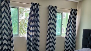 A hotel room with a bed, a desk, and curtains.