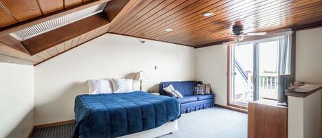 A bedroom with a bed, a sofa, a desk, and a window.