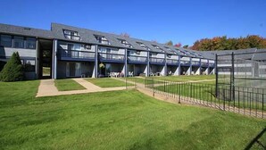A multi-story building with a flat roof, a covered outdoor area with tables and chairs, and a fenced play area. - Nautical Mile (Wells)