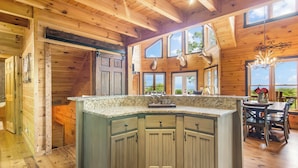 A wooden cabin interior with a kitchen island, dining area, and large windows. - Family-Friendly Blue Ridge Log Cabin w Stunning Views-Free Flexible Check In-Out (Blue Ridge)