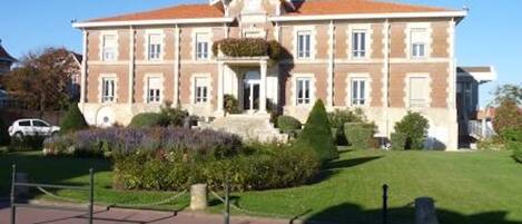 Un grand bâtiment à deux étages, doté d’une façade symétrique, d’une entrée centrale et d’un toit triangulaire.
