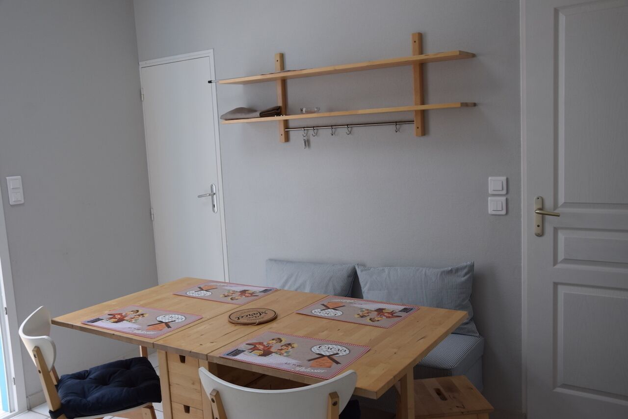 A dining area with a wooden table, chairs, and a bench. There are two wooden shelves above the table.