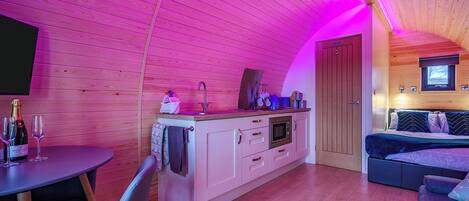 Un intérieur de chalet chaleureux comprenant une cuisine, un coin repas et un espace nuit.