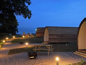 Un camping con cabañas de madera, mesas de picnic y una parrilla.