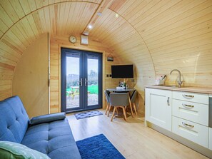 Un intérieur de chalet chaleureux avec un canapé, une table à manger et un coin cuisine.