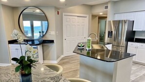 A modern kitchen with a marble countertop, a sink, and stainless steel appliances. - Beautiful and Spacious Beachfront Rental! Beach Chair Service Included! (Orange Beach)