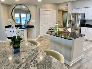Enjoy a spacious kitchen with a central island, modern appliances, and a dining area featuring a marble table and chairs.