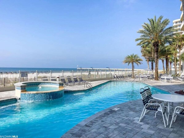 Relax by the pool or unwind in the hot tub, surrounded by palm trees and a serene beach view.