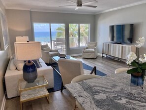 Relax in this ocean-view living room with a sofa, chairs, coffee table, TV, and dining table.