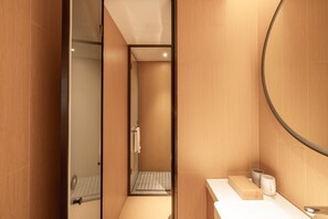 A modern bathroom with a glass shower enclosure, a wooden vanity, and a large mirror.