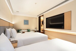 A hotel room with two beds, a TV, a small table, and a wall-mounted TV.