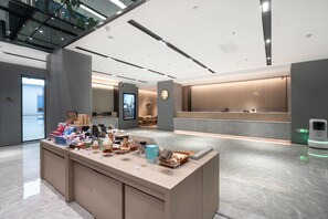 A modern hotel lobby with a reception desk, a digital display, and a self-service kiosk. - Ji Hotel (Guangzhou)