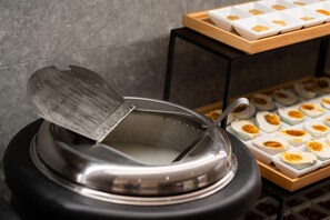 Un ensemble pour préparer une fondue, comprenant un couvercle, un plateau de tranches d’œufs et un mur recouvert de carreaux.