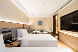 A hotel room with a bed, bedside table, TV, and a small seating area with a table and chairs. - Ji Hotel (Guangzhou)