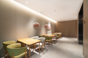 A modern interior with a row of tables and chairs, recessed ceiling lights, and a minimalist design. - Ji Hotel (Guangzhou)