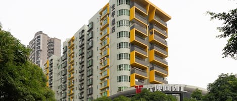 A multi-story building with balconies, a visible sign with Chinese characters, and surrounding greenery.