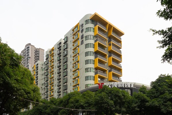 A multi-story building with balconies, a visible sign with Chinese characters, and surrounding greenery.