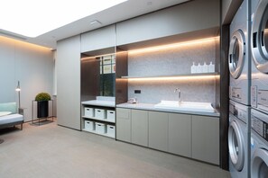 A modern laundry room with a sink, washing machines, and storage cabinets. - Ji Hotel (Guangzhou)