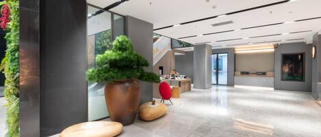Un vestíbulo moderno con una planta grande en maceta, una recepción y una escalera.