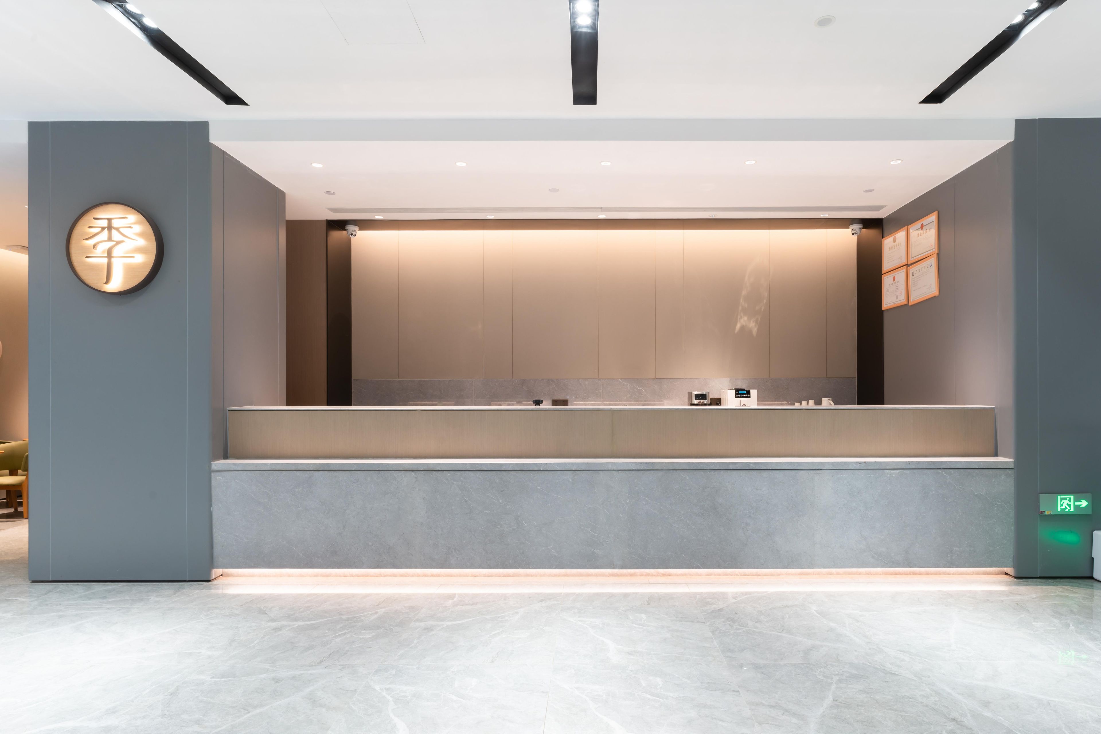 A reception desk with a modern design, a wall-mounted sign, and a framed certificate on the wall.