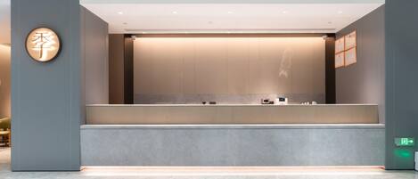 A reception desk with a modern design, a wall-mounted sign, and a framed certificate on the wall.