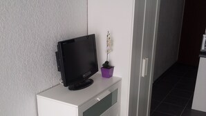 A white cabinet with a flat-screen TV and a small potted plant on top. - WATERFRONT STUDIO APARTMENTS CARNON PLAGE NEAR LA GRANDE MOTTE (CARNON PLAGE)