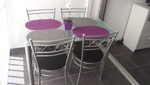 A dining table with four chairs, a small potted plant, and a white cabinet in the background. - WATERFRONT STUDIO APARTMENTS CARNON PLAGE NEAR LA GRANDE MOTTE (CARNON PLAGE)
