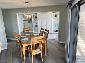 Un comedor con mesa y sillas de madera, un candelabro y una puerta blanca que da a un cuarto de almacenamiento.