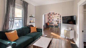 A living room with a green sofa, a coffee table, and a TV mounted on the wall.