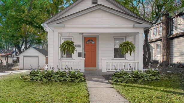 A single-story house with a front porch, two potted plants, and a mailbox.