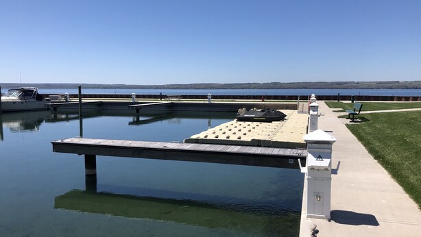 Una marina con un muelle, un jet ski y una zona verde con un banco.