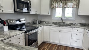 Una cocina moderna con armarios blancos, una estufa de acero inoxidable y un microondas.